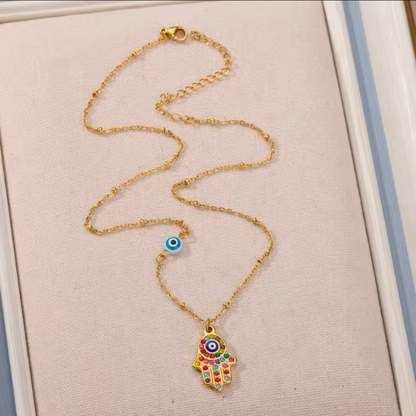 Gold necklace with a colorful evil eye pendant on a beige background
