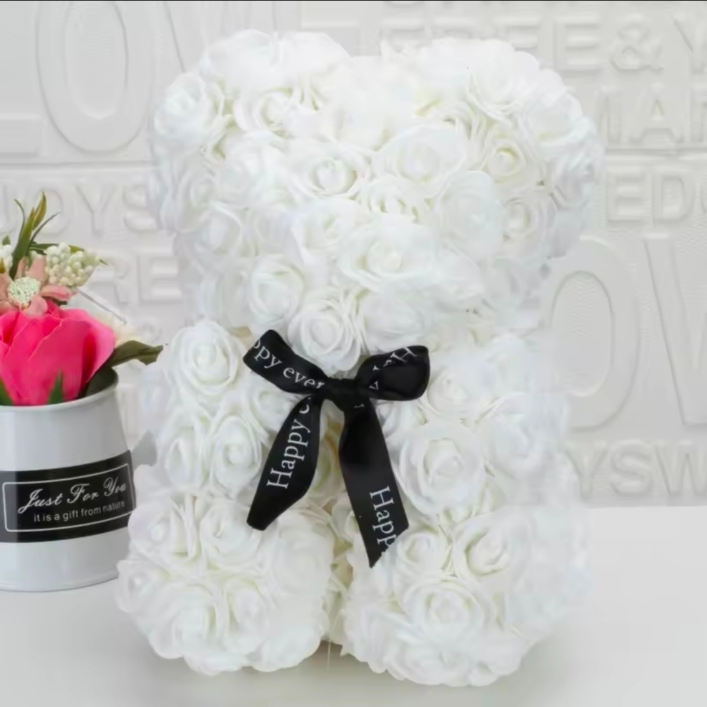 Bear-shaped arrangement of white roses with a black ribbon on a textured white background
