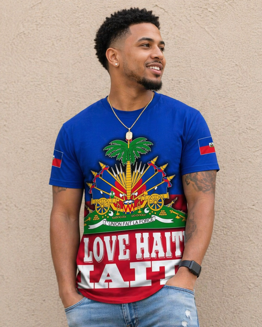 Man wearing a blue t-shirt with colorful graphics and 'Love Haiti' text against a beige wall.