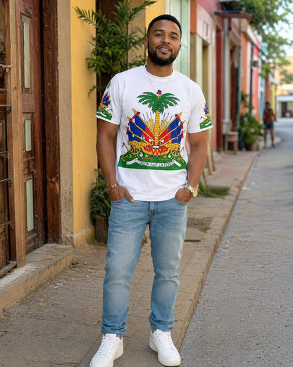 Man wearing a white t-shirt with a colorful Haiti emblem graphic design and light blue jeans standing on a street.