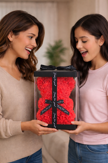 Two women holding a large transparent box filled with red roses and black ribbons.