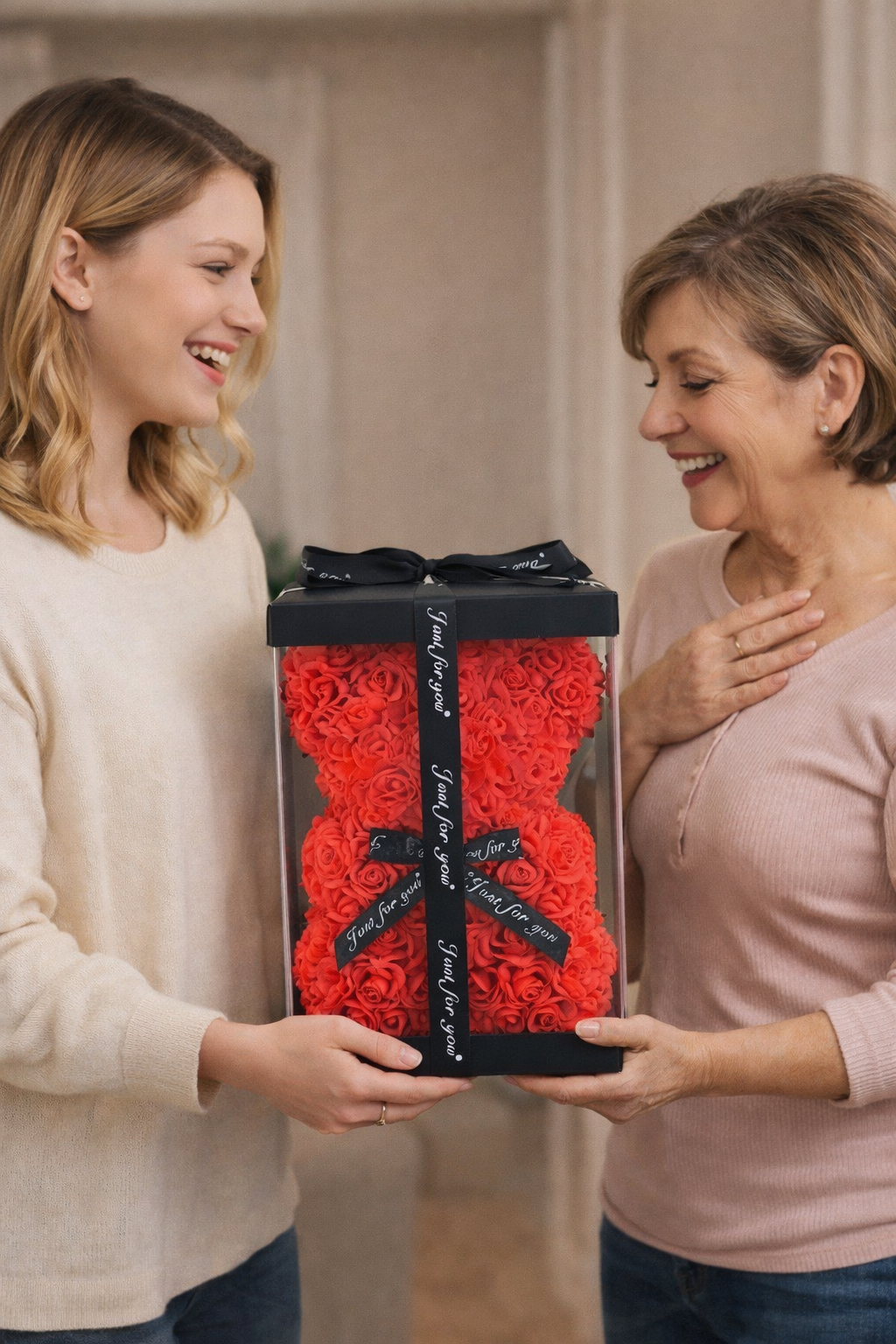 Two women holding a large red gift box with a black ribbon.
