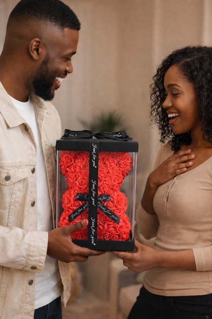 Man and woman holding a gift box with red roses and black ribbons.